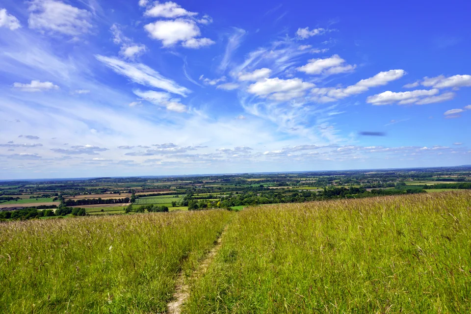 Open countryside beneath sweeping white clouds